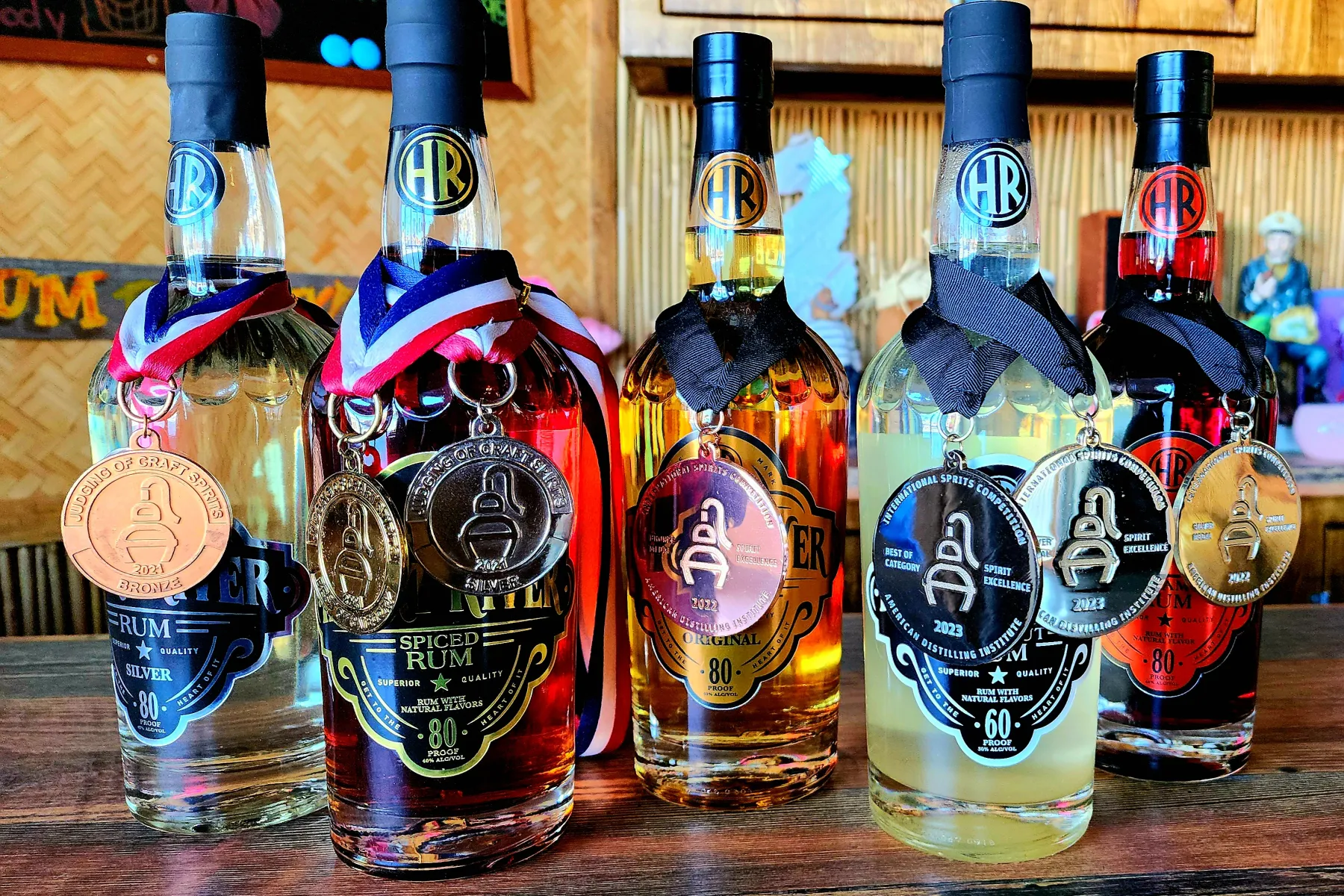 Five Heart River Rum bottles lined up on the bar, each wearing its award medal